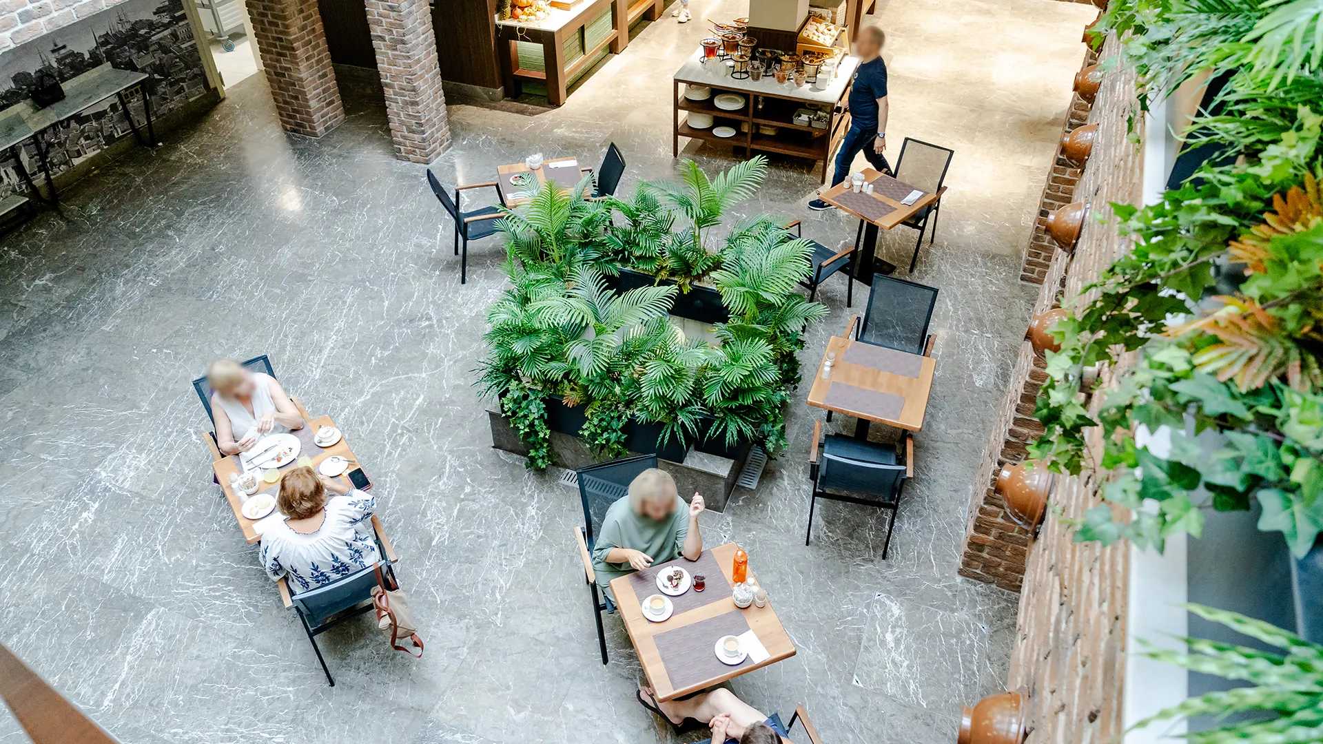Una vista aerea di persone che mangiano ai tavoli in un ristorante di un hotel.