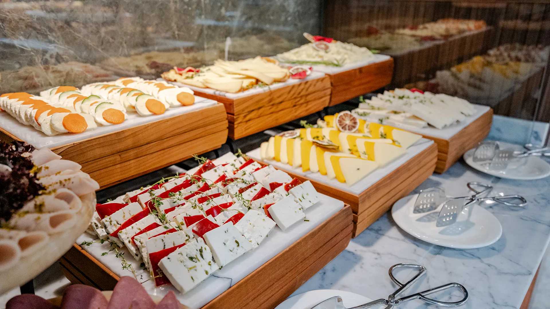 Um buffet de queijos com uma variedade de tipos diferentes de comida.